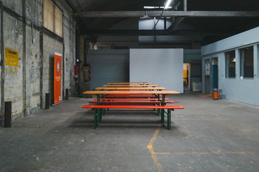 Empty industrial space with wooden benches, perfect for events or gatherings.