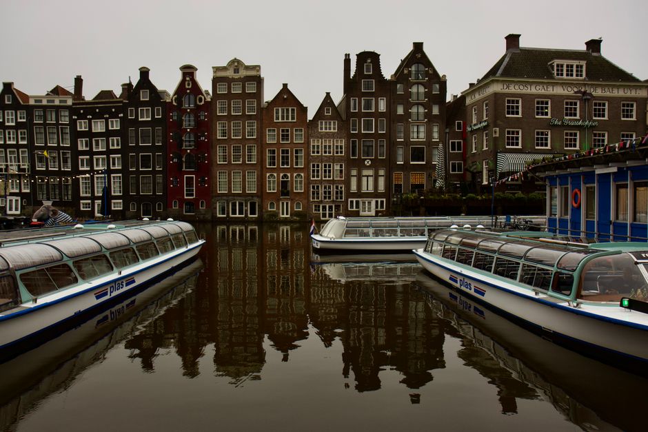 Charming Amsterdam canal scene with iconic Dutch architecture and tour boats.