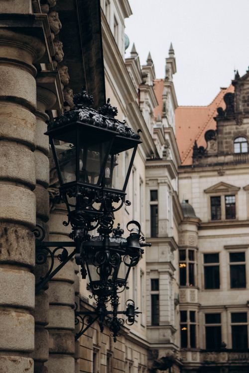 Free Elegant Gothic architecture facade with intricate wrought iron lanterns captured in an urban setting. Stock Photo