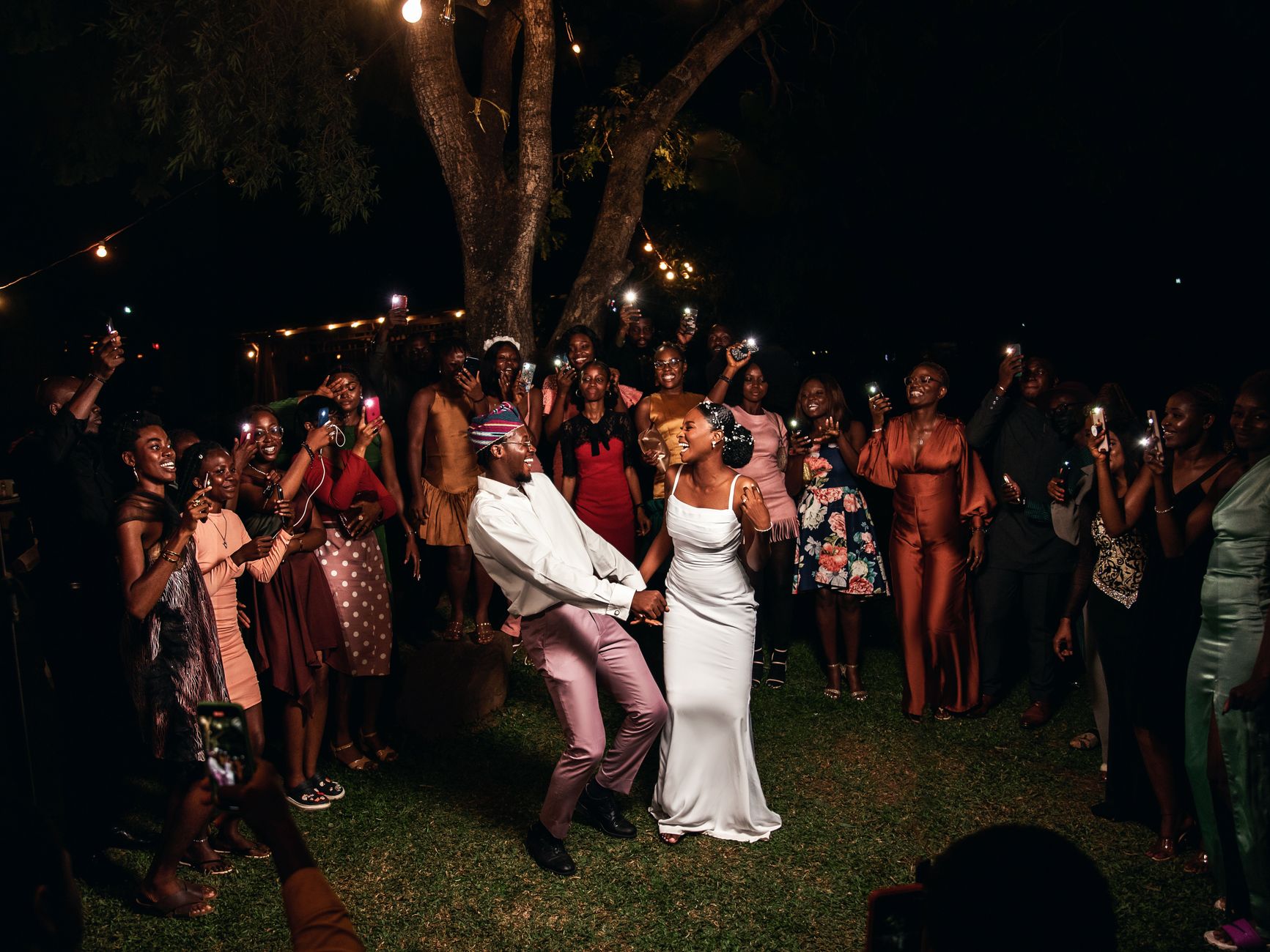A vibrant wedding party celebrating under lights in Nigeria.