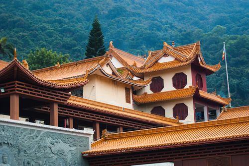 Free Serene traditional Chinese temple with ornate roofs against lush mountainous backdrop. Stock Photo