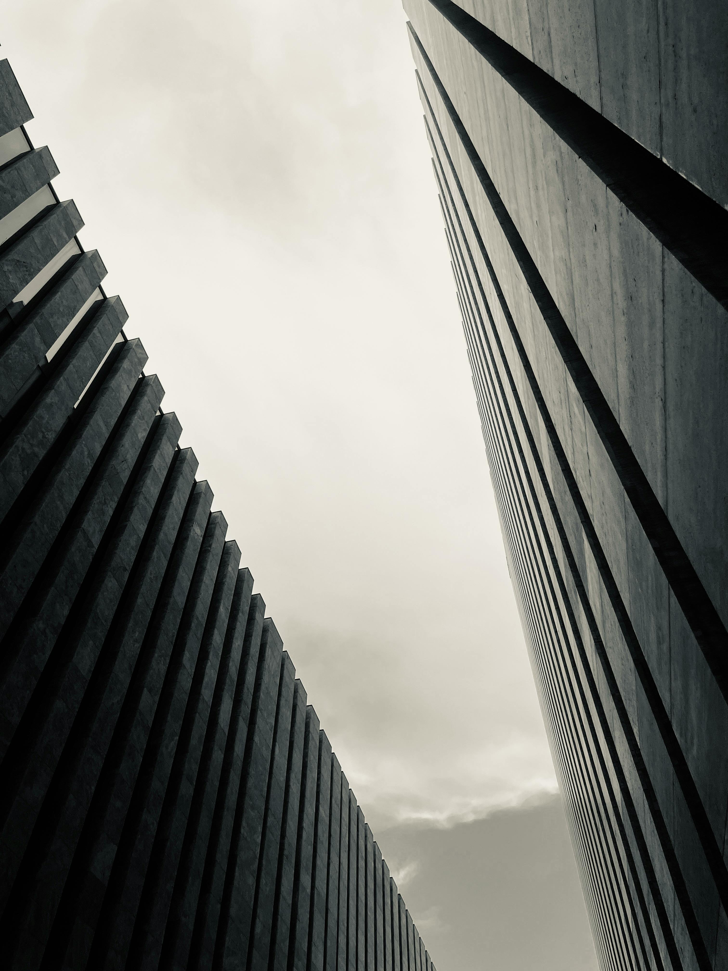 bezplatná Monochromatický pohled na tyčící se moderní architekturu s dramatickou oblohou nad hlavou. Základová fotografie