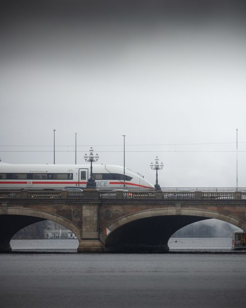 Free A high-speed train crossing a historic bridge over the Elbe River in misty Hamburg, Germany. Stock Photo