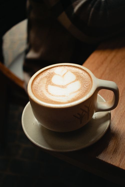 Free A beautifully crafted cappuccino with latte art in a rustic café setting. Stock Photo