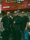 Three Men in Black Attire With Sunglasses in Urban Setting