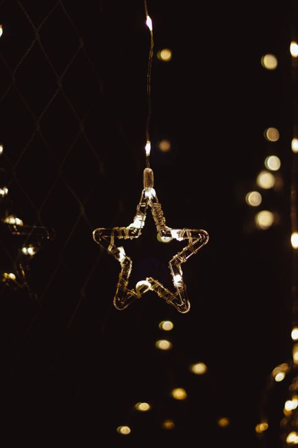 Fotomural Una cadena de luces brillantes en forma de estrella que cuelga en la oscuridad y crea un ambiente acogedor.