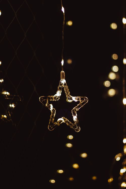 Free A glowing star-shaped string light hanging in the dark, creating a cozy ambiance. Stock Photo