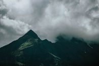 戏剧性的云层笼罩着山峰，营造出喜怒无常的景观