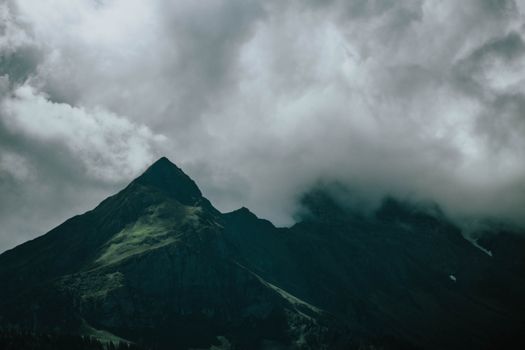 戏剧性的云层笼罩着山峰，营造出喜怒无常的景观