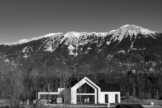 Black and white photo of a modern house with Slovenian mountains in the background.