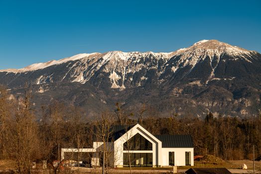 A modern house set against the backdrop of snowy mountains in Bled, Slovenia.