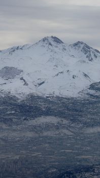 A majestic view of snow-covered mountains with a city nestled below in Türkiye.