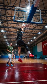 Energetic slam dunk captured during a basketball game at an indoor court in Konya, Türkiye.