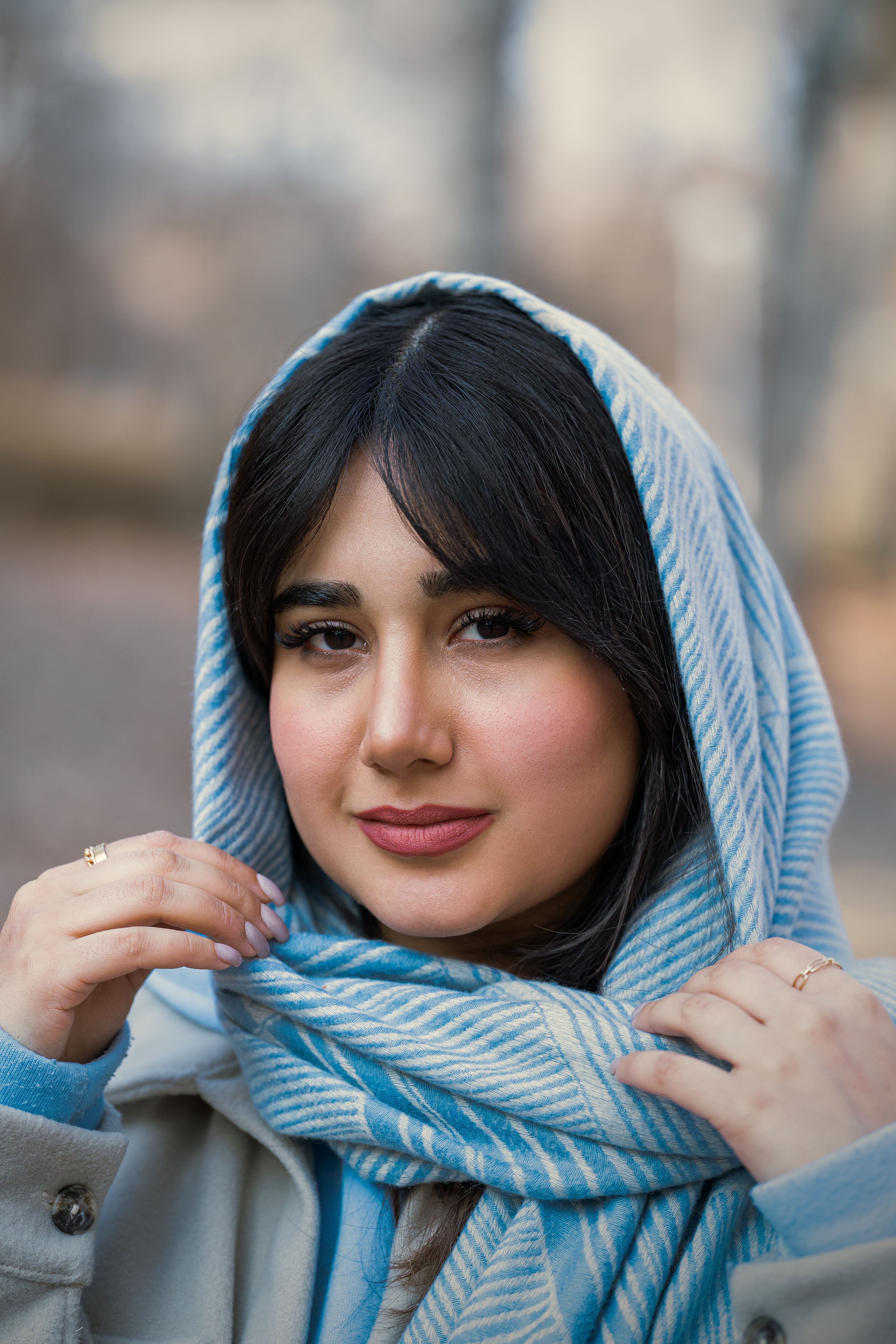 A stylish woman in a blue scarf, outdoors in Türkiye, exuding elegance.
