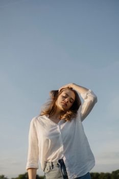 Outdoor portrait of a woman in casual attire posing against a clear blue sky in Leipzig, Germany.