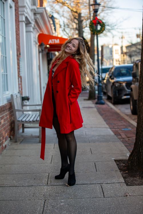 Free A cheerful woman in a bright red coat poses on a city street during the winter holiday season. Stock Photo