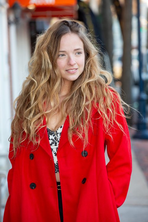 Free Casual portrait of a woman in a vibrant red coat walking outdoors. Stock Photo