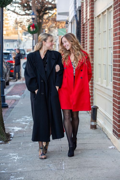 Free Two women in stylish coats enjoying a winter walk on a city sidewalk. Stock Photo