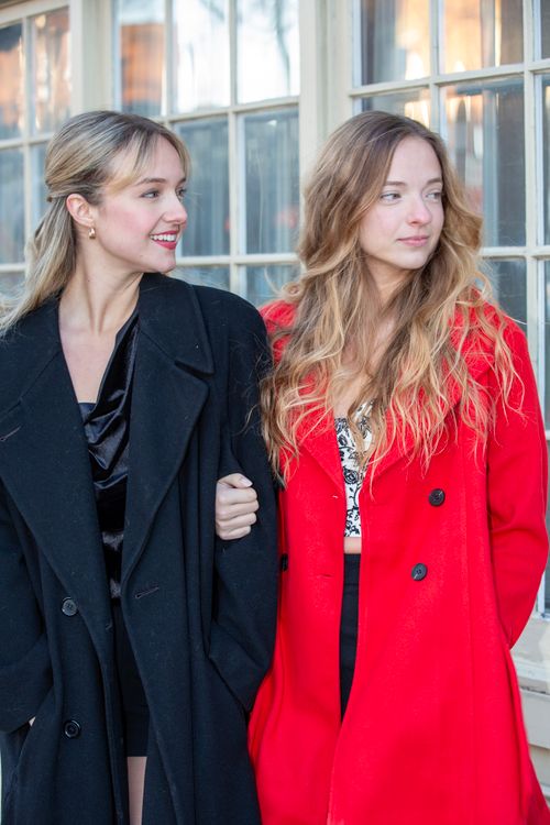 Free Two women in fashionable black and red coats enjoying a casual day outdoors. Stock Photo