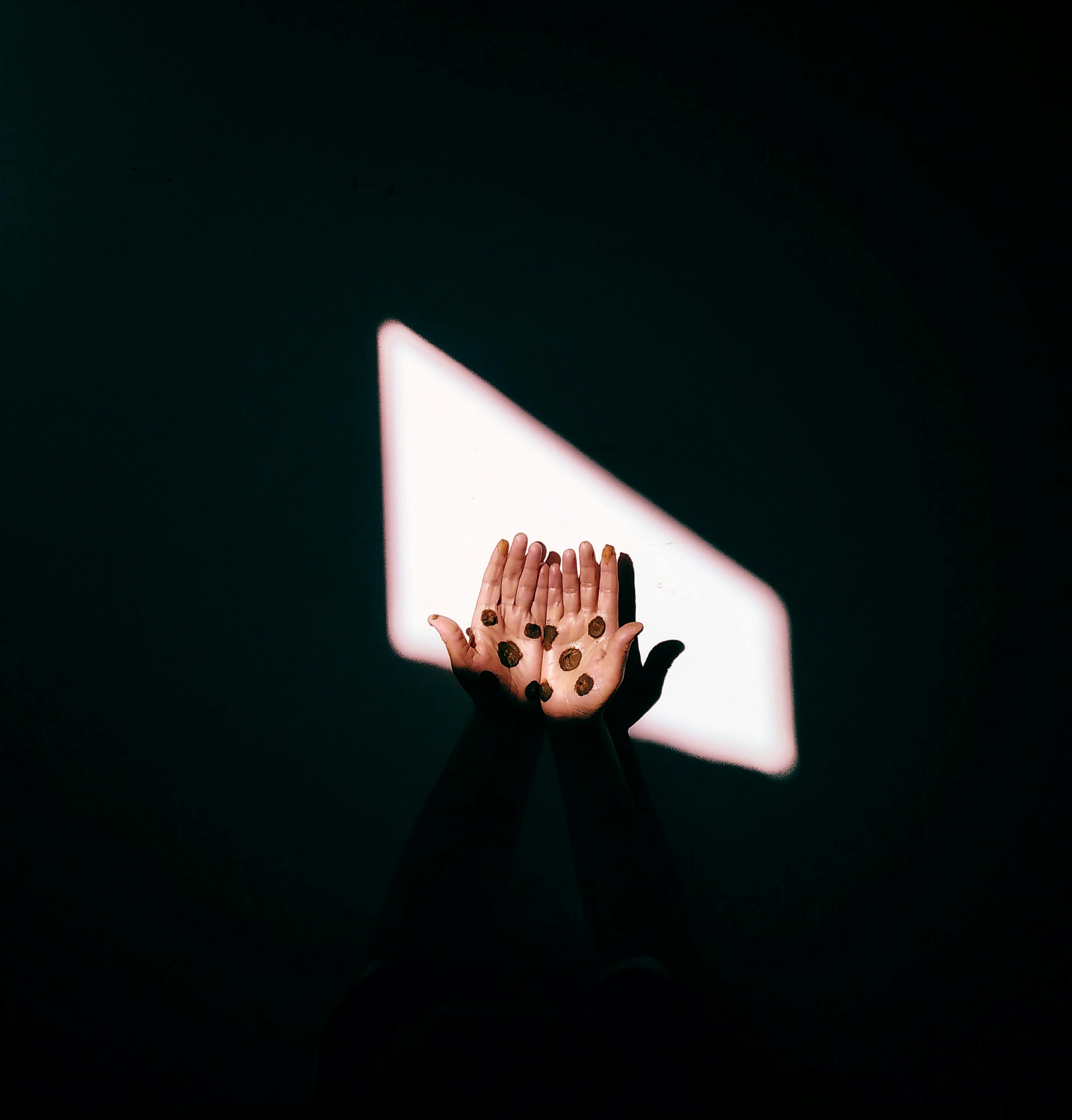 gratis Uitgestrekte handen met munten, verlicht door dramatische verlichting, symboliseren rijkdom en hoop. Stockfoto