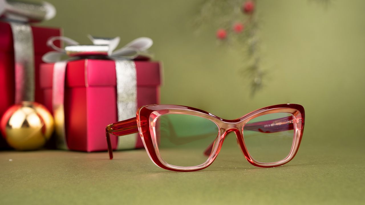 close up of red glasses with festive gifts and decorations in the back