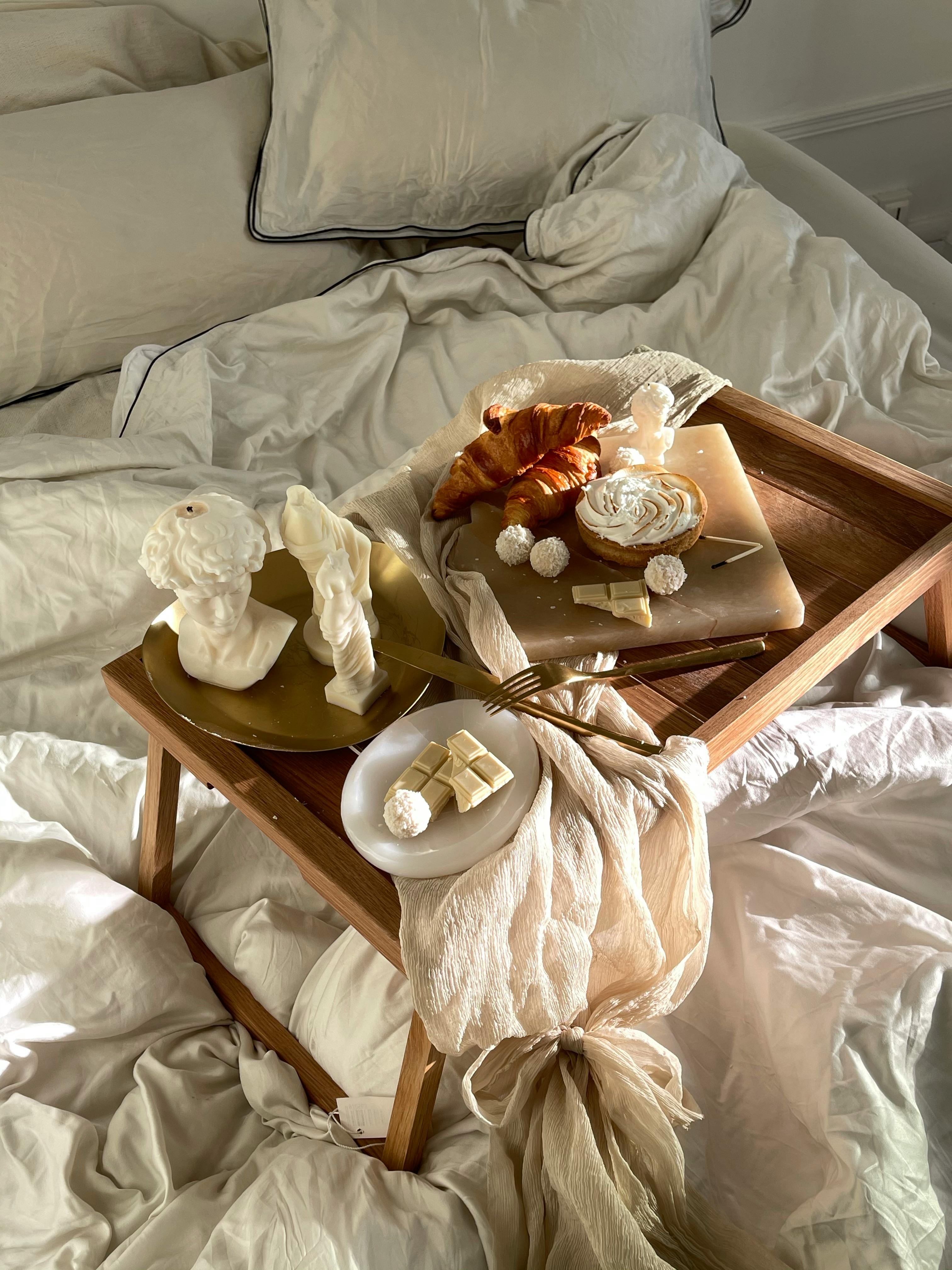 Elegant breakfast setup with croissants and artistic decorations on a bed tray.