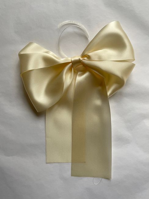 A large cream satin bow elegantly displayed on a crisp white background.