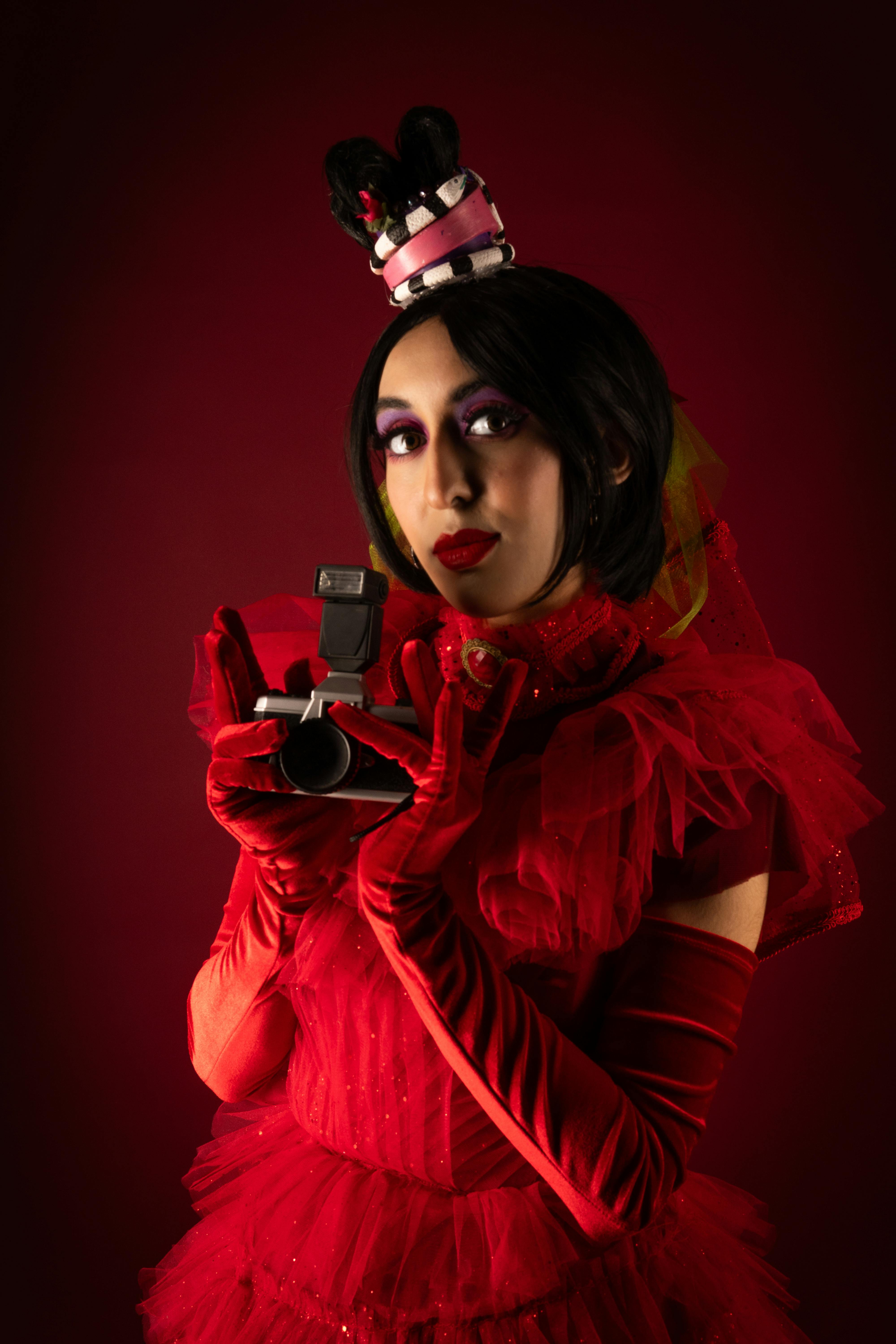 Ücretsiz Kırmızı kostümlü, elinde eski bir kamera tutan bir cosplayer'ın canlı portresi. Stok Fotoğraflar