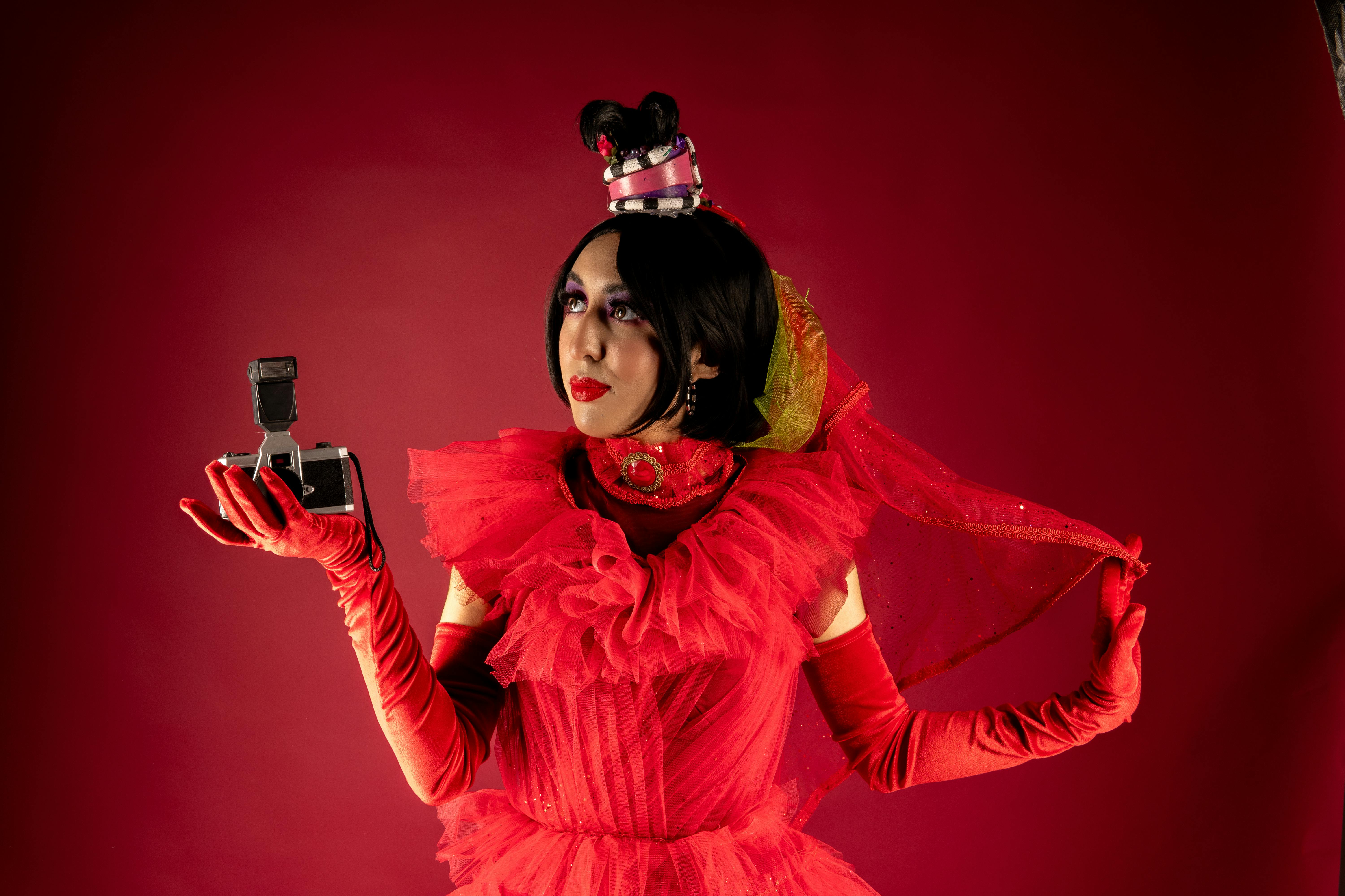 Ücretsiz Çarpıcı kırmızı kıyafetler ve cesur bir arka plan önünde eski kamera ile dramatik cosplay sahnesi. Stok Fotoğraflar