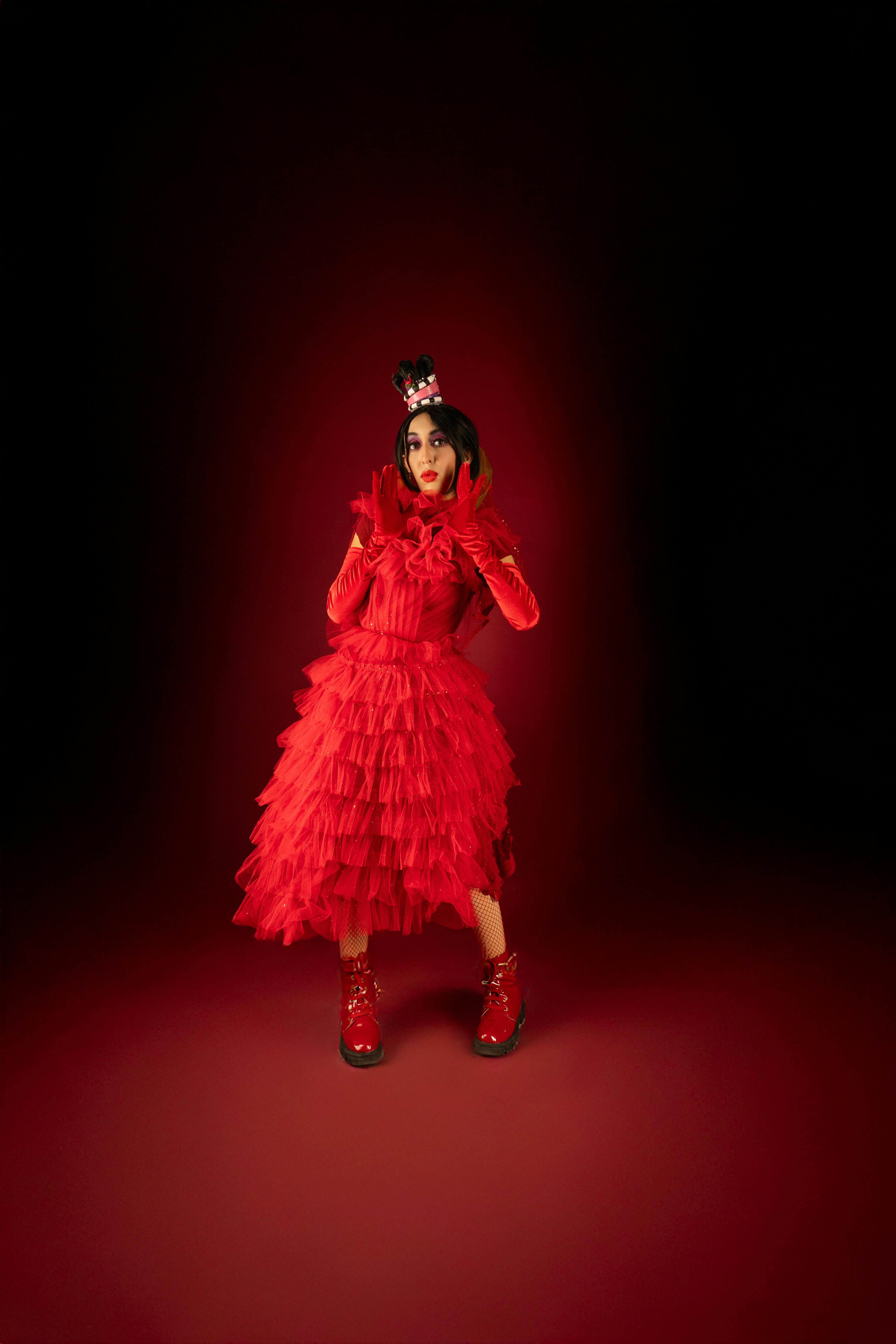 Ücretsiz Katmanlı kırmızı bir elbise, siyah peruk ve aksesuarlar giyen bir karakterin yer aldığı çarpıcı bir cosplay portresi. Stok Fotoğraflar