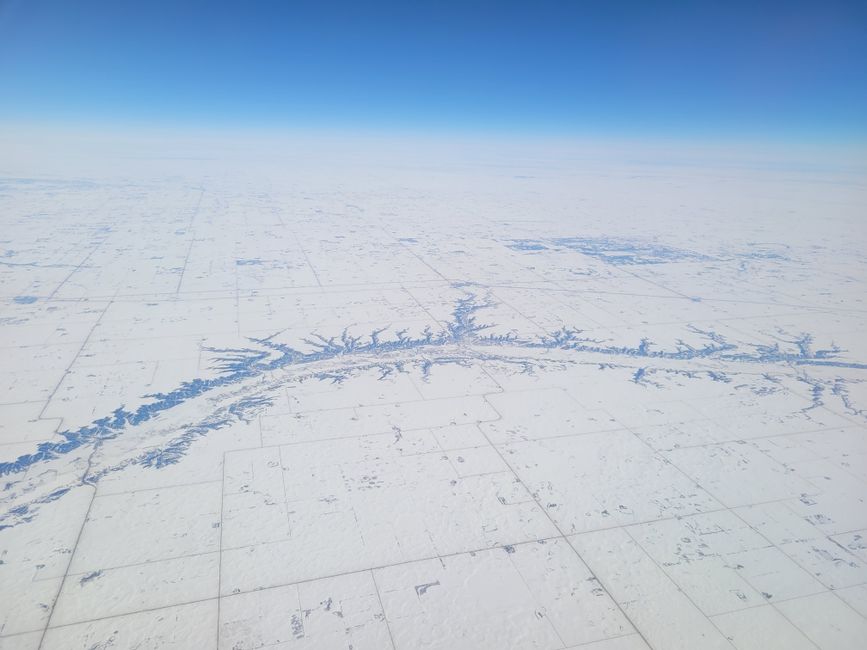 A breathtaking aerial shot showcasing a vast snow-covered landscape under a clear blue sky during winter.