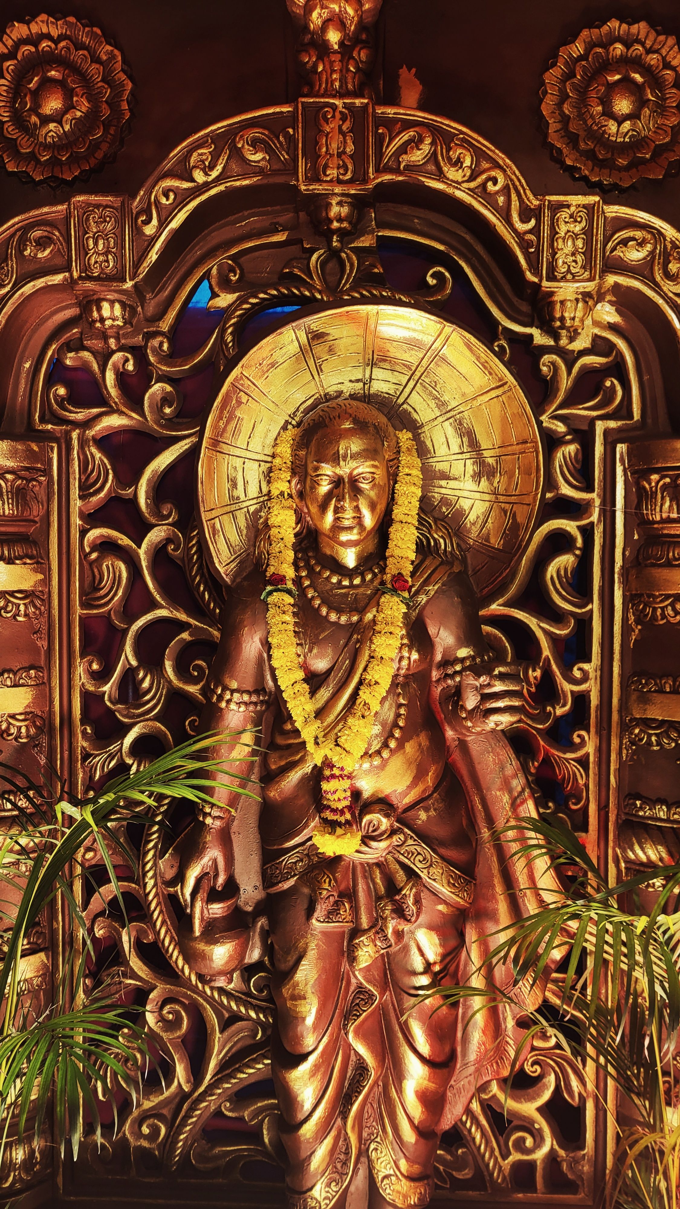Detailed bronze statue of a Hindu deity adorned with garlands, showcasing traditional Indian artistry.