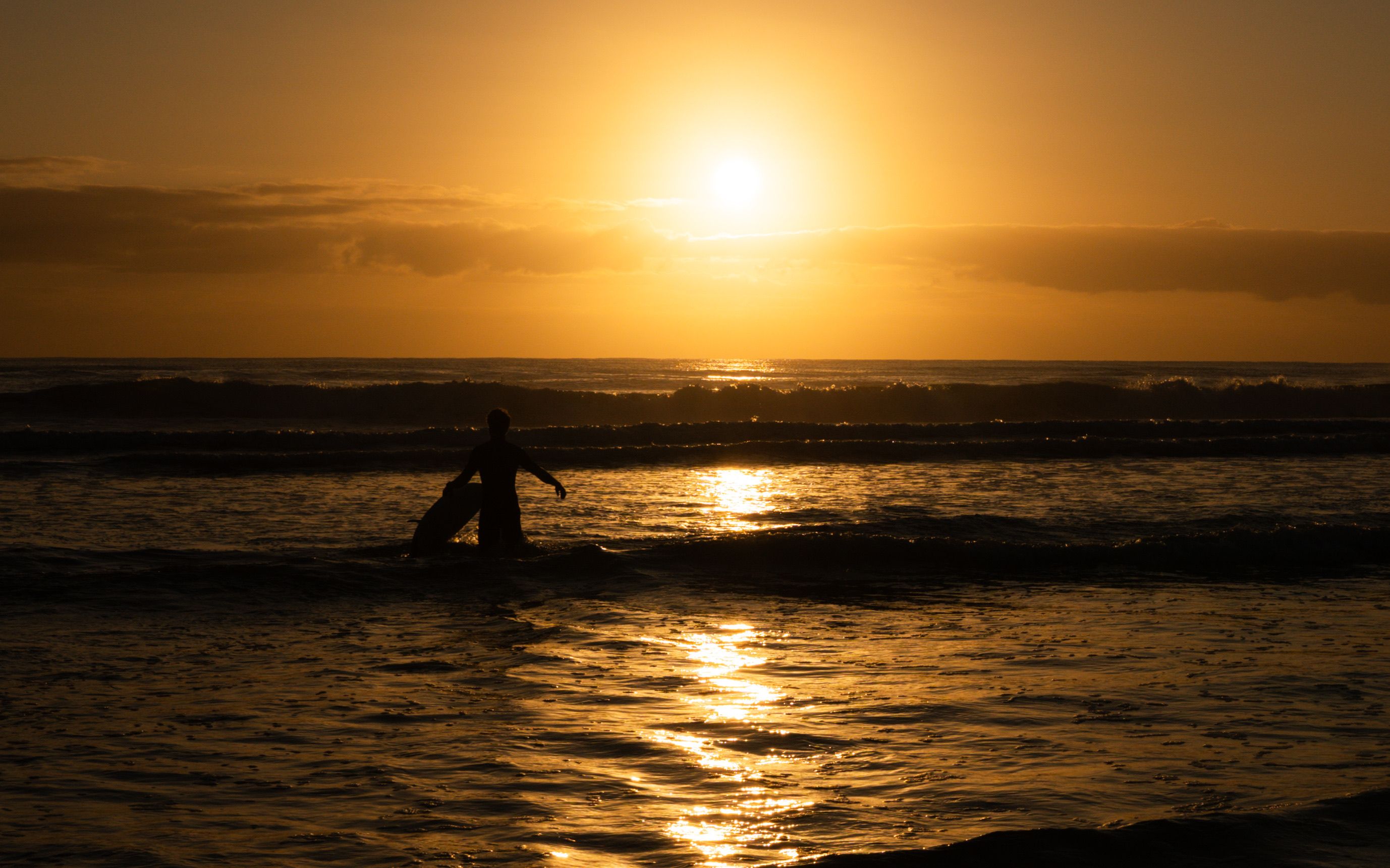 Silhouetted Surfer at Sunset on Ocean Waves · Free Stock Photo
