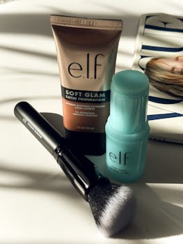 E.L.F. makeup set featuring foundation, primer stick, and brush on a magazine under sunlight.