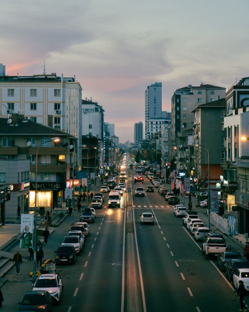 Free A bustling city street at twilight with cars and people creating an urban atmosphere. Stock Photo