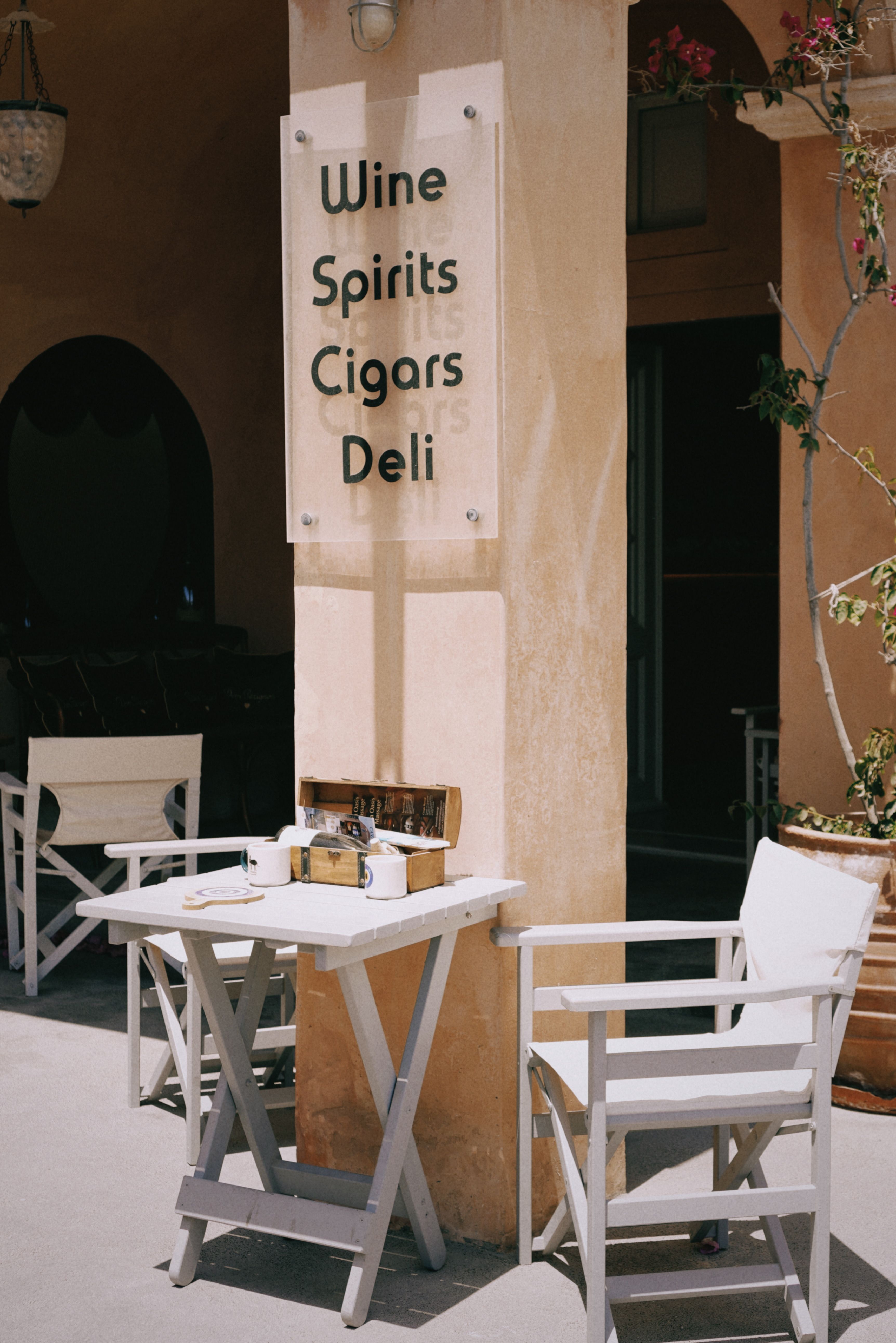 Elegant outdoor setting at a cafe highlighting wine, spirits, cigars, and deli options.