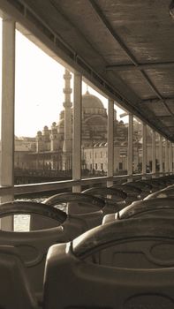 A sepia-toned view of Istanbul's architecture from a ferry, highlighting a mosque.
