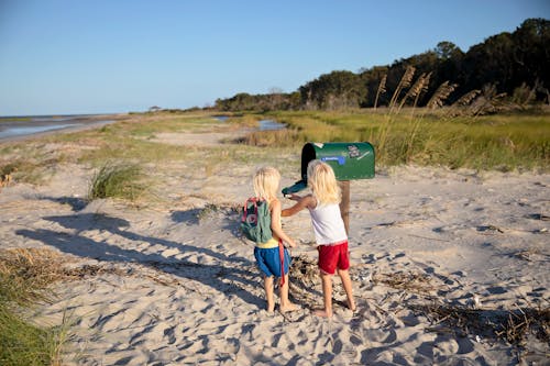 兩個孩子站在綠色郵箱旁邊