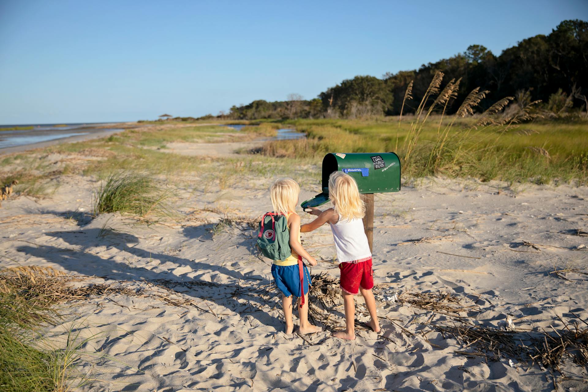 Two children play by a beachside mailbox at Hilton Head Island, enjoying a sunny day outdoors.