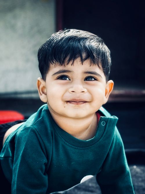 Free Cute toddler smiling outdoors in warm lighting wearing a green sweater. Stock Photo