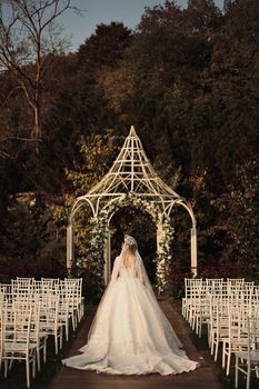 A bride walks down the aisle towards a beautifully decorated gazebo in an outdoor wedding setting in Istanbul, Turkey.