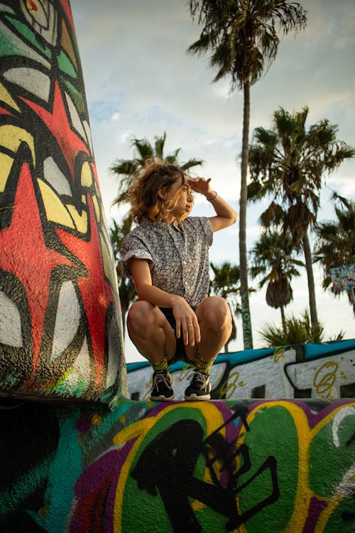 Foto Van Vrouw Gehurkt Op Graffiti Muur Poseren Terwijl Wegkijken