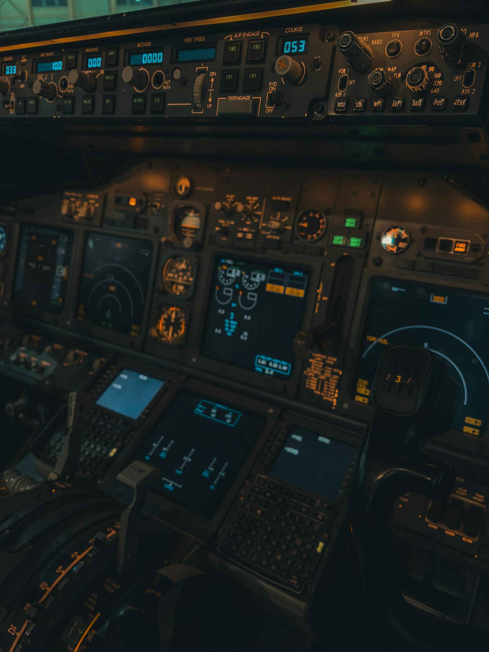 Pilot operating flight deck controls at dusk