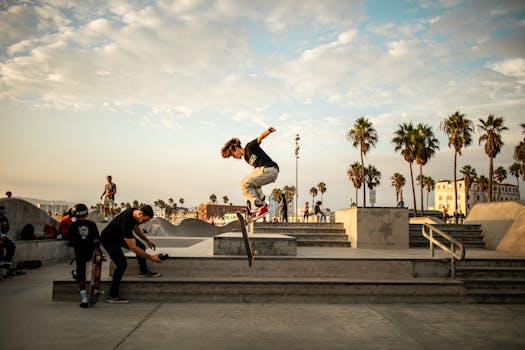 Skateboarder performs trick in vibrant Venice Beach skatepark during golden hour.