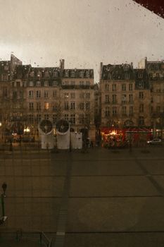 Charming Parisian street scene captured through a window during evening hours.