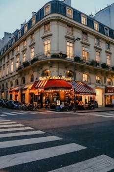 A cozy Parisian cafe facade at dusk in the heart of the city, capturing vibrant evening life.