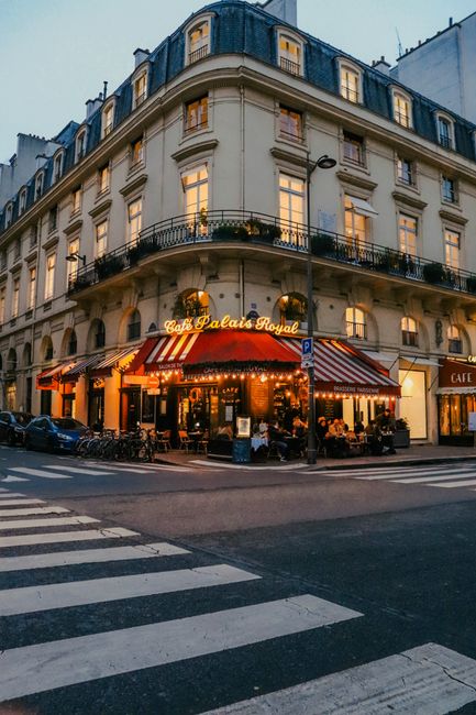 A cozy Parisian cafe facade at dusk in the heart of the city, capturing vibrant evening life.