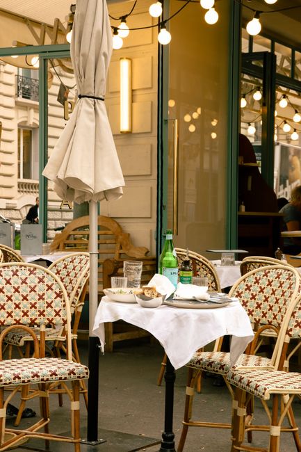 Cozy outdoor seating at a Paris café with classic rattan chairs and a white tablecloth.