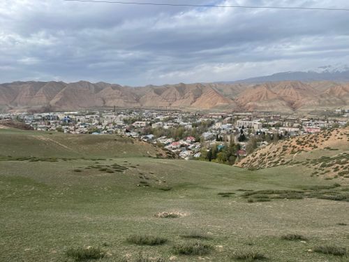 Free A picturesque view of Naryn city surrounded by hills and greenery under a cloudy sky. Stock Photo