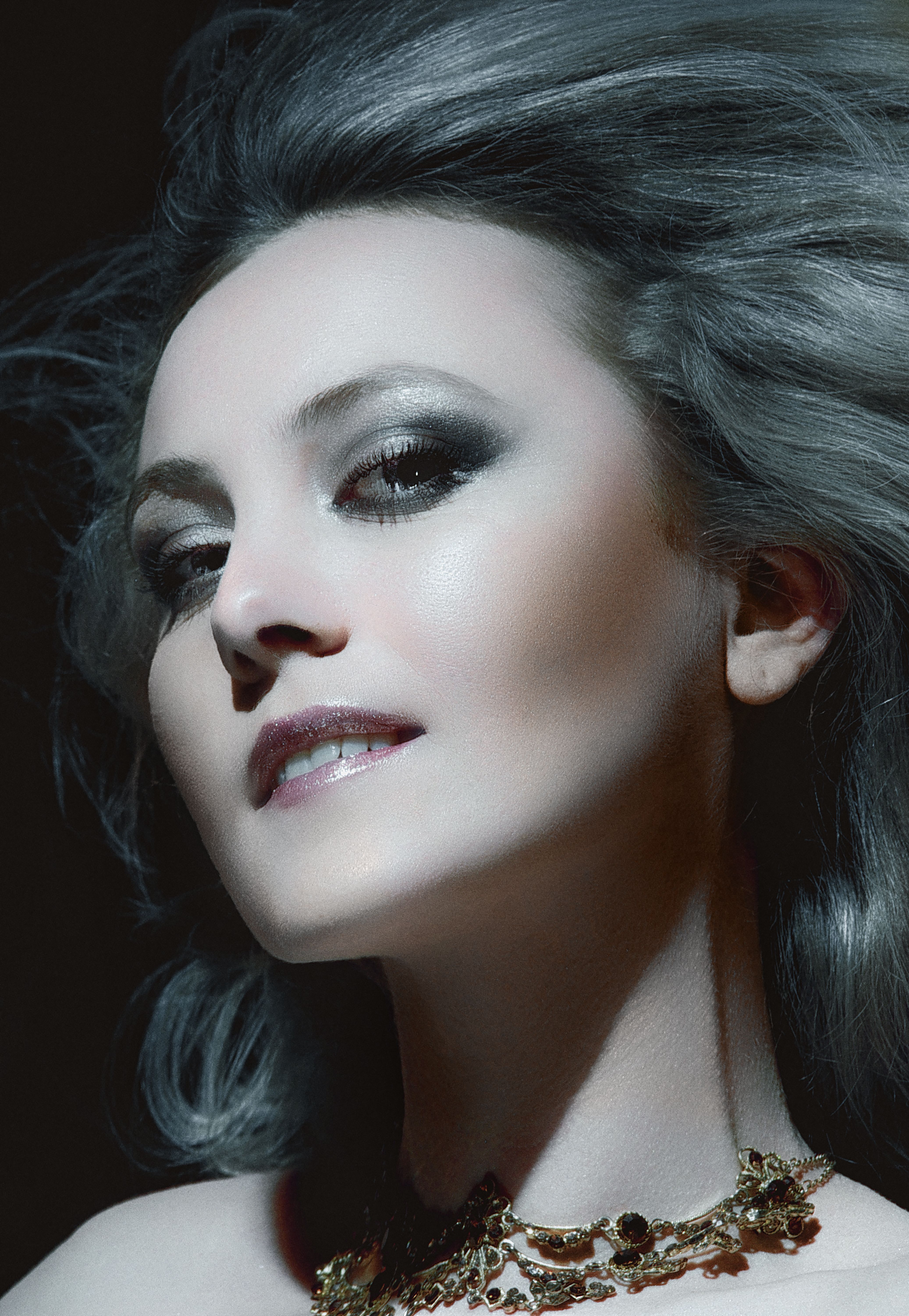 Striking portrait of a woman with silver hair and elegant jewelry.